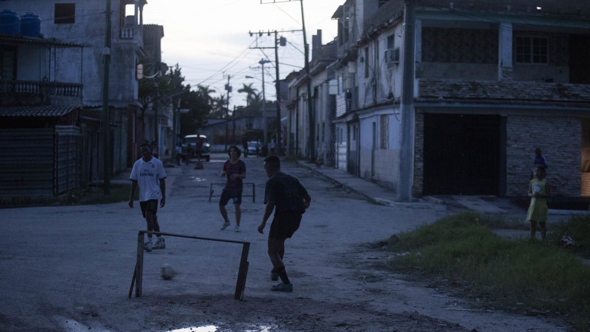 Varios jóvenes que juegan fútbol durante un apagón.