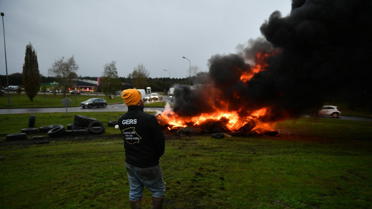 Un manifestante se encuentra junto a un incendio durante una protesta convocada por el sindicato de agricultores francés 'Coordinación Rural'.