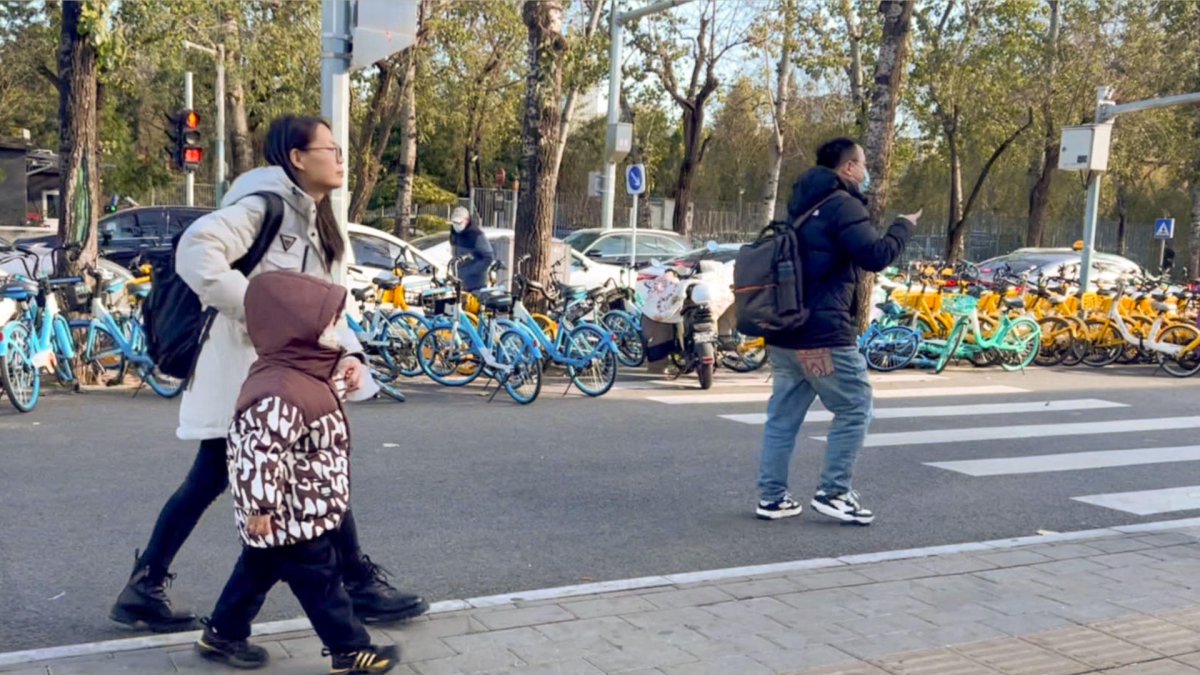 Una madre camina con su hijo camino a la escuela, en Pekín. El país, que en 2023 cedió a la India el título de nación más poblada del mundo, según la ONU.