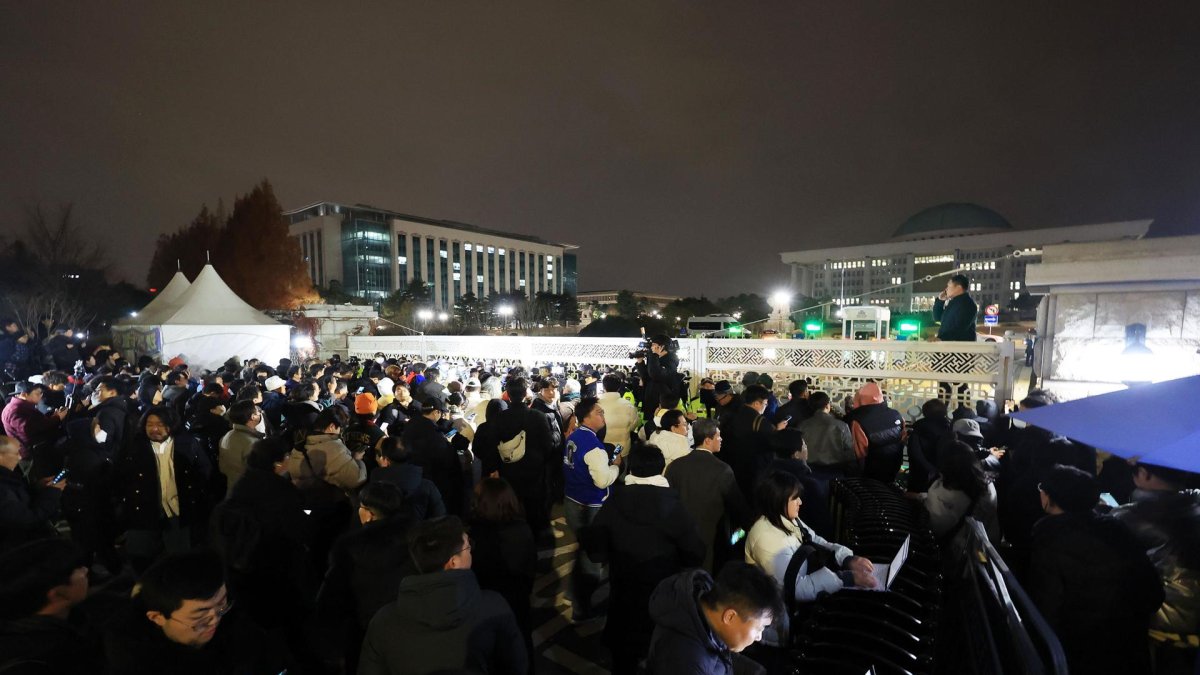 La puerta principal de la Asamblea Nacional en Seúl está abarrotada de gente mientras la policía bloquea la entrada tras la declaración de ley marcial en Seúl, el 3 de diciembre de 2024.