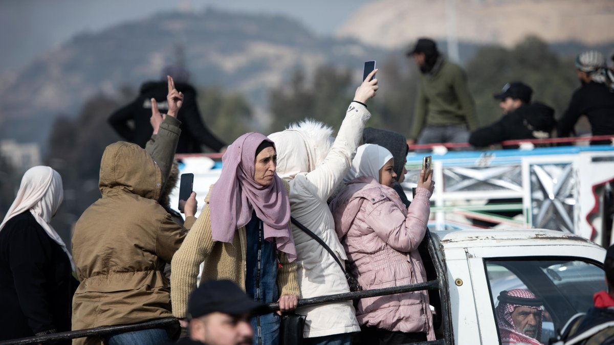 Personas celebran montadas en la parte trasera de un vehículo tras la captura de la ciudad de Damasco por parte de los rebeldes sirios.
