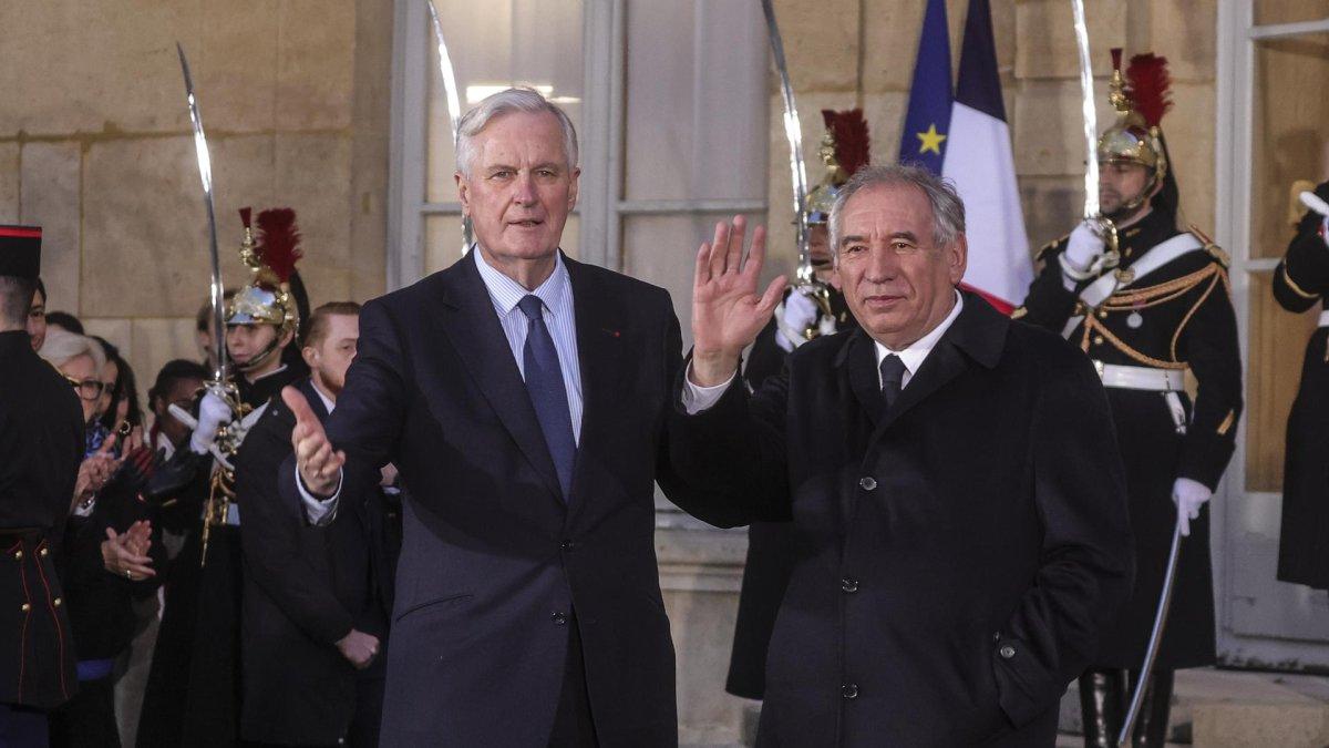 El primer ministro saliente de Francia, Michel Barnier (izq.), y el nuevo primer ministro, François Bayrou, saludan durante la ceremonia de traspaso en el Hotel Matignon, el 13 de diciembre de 2024.