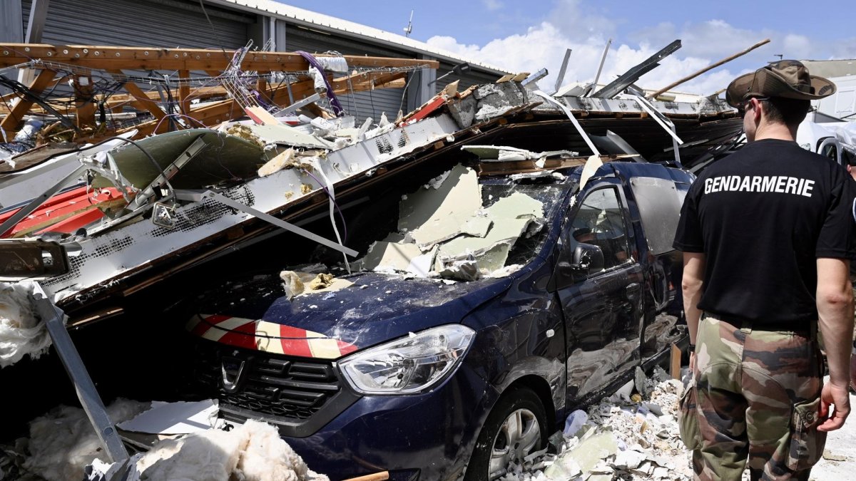 Pamandzi (Mayotte). Un gendarme francés observa el coche de la Gendarmería bajo edificios derrumbados