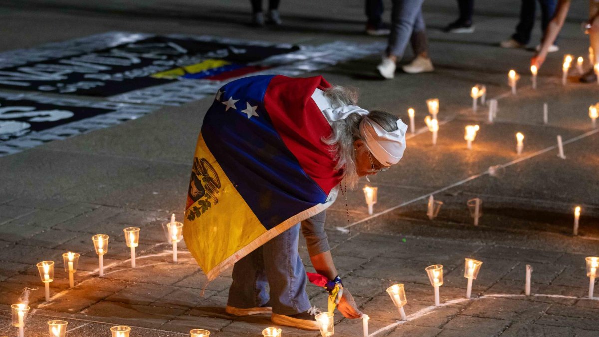 Una mujer enciende una vela durante una vigilia por los 