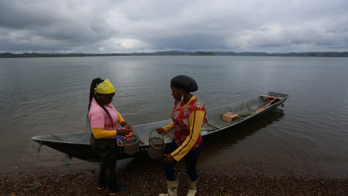 Fotografía del 9 de diciembre de 2024 de dos mujeres recolectoras de piangua bajando de una canoa, en la vereda La Plata de Bahía Málaga (Colombia).