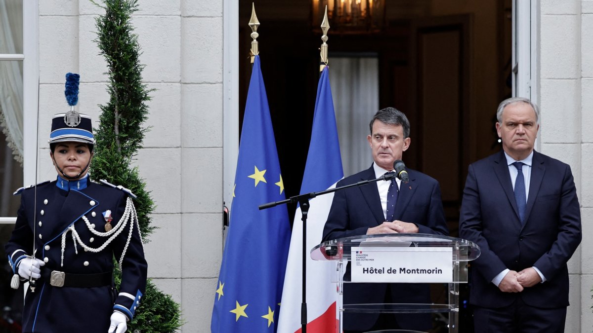 El recién nombrado Ministro de Ultramar, Manuel Valls (C), pronuncia un discurso acompañado por el Ministro saliente adjunto al Ministro del Interior, Francois-Noel Buffet