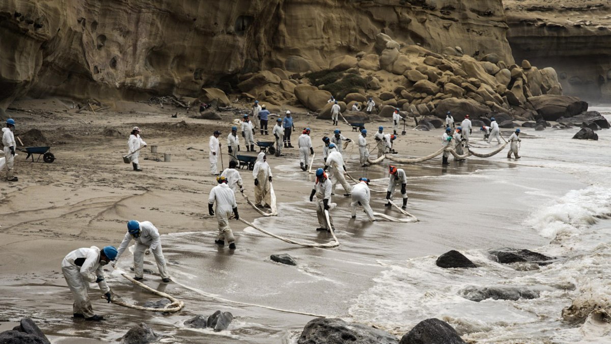 Integrantes de Petroperú limpian un derrame de petroleo en la playa La Capullana, distrito de Lobitos, en la provincia de Talara, en el norte de Perú.