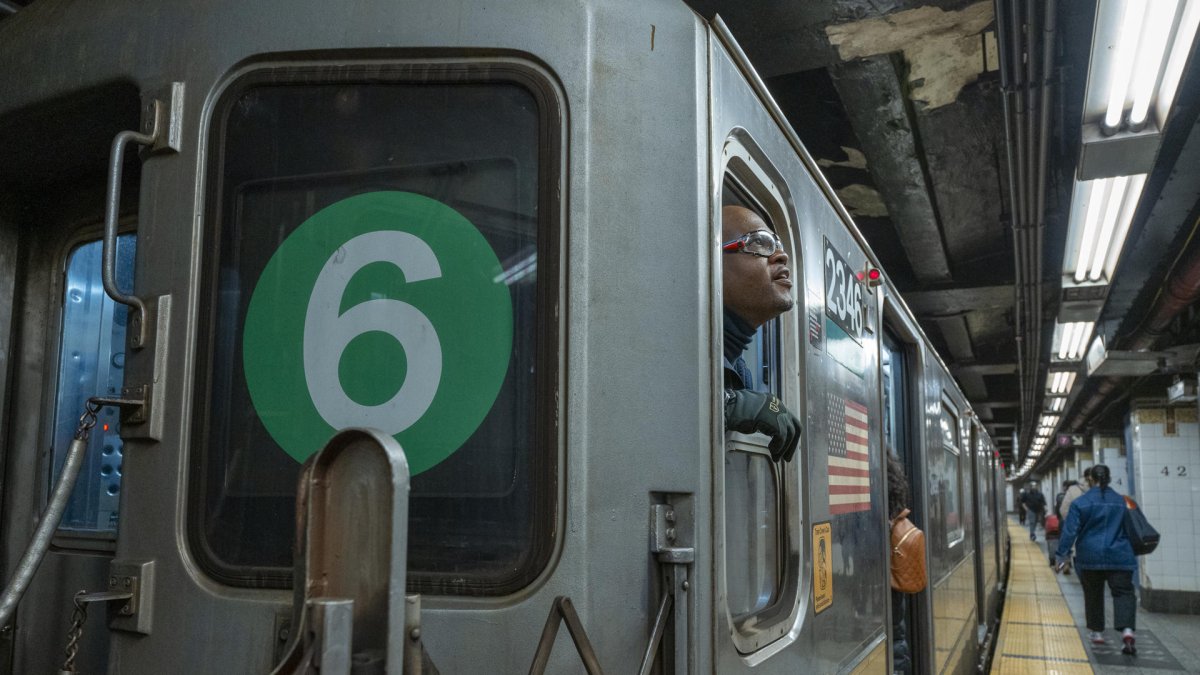 Una persona aparece asomada del otro lado de la ventana de un vagón del metro de Nueva York.