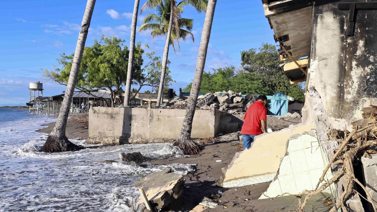Un hombre camina por viviendas destruidas en la costa de la comunidad de Cedeño (Honduras).
