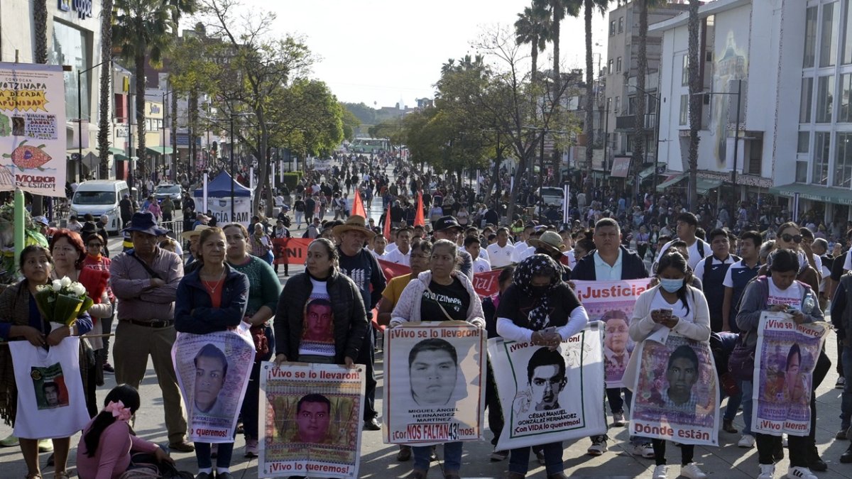 Familiares de las víctimas de Ayotzinapa sostienen retratos de los estudiantes desaparecidos mientras participan en una peregrinación frente a la Basílica de Nuestra Señora de Guadalupe.