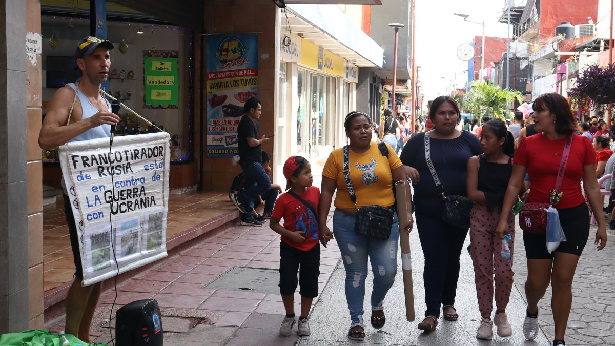 El migrante de origen ruso Tajir (i) canta para recibir ayuda este viernes, en el municipio de Tapachula en Chiapas (México).