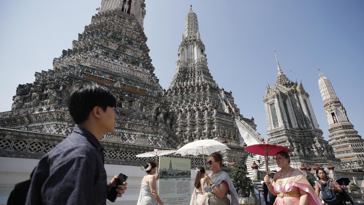 Turistas extranjeros vestidos con trajes tradicionales tailandeses visitan el Templo del Amanecer, o Wat Arun, en Bangkok, Tailandia, el 6 de enero de 2025.