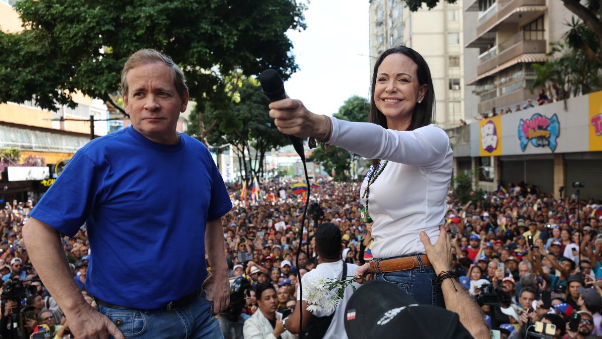La líder antichavista María Corina Machado (d) saluda a sus seguidores junto al exdiputado venezolano Juan Pablo Guanipa este jueves, en una manifestación en Caracas (Venezuela).