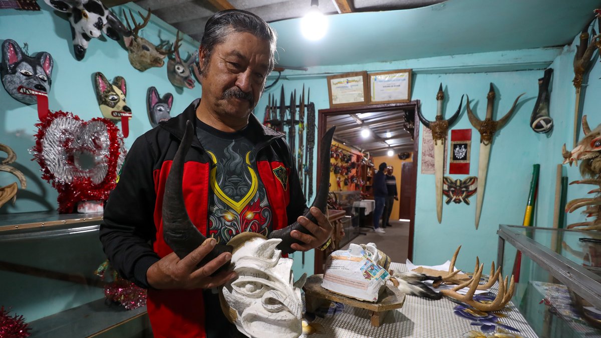 El artesano Ángel Velasco sostiene una mascara en Píllaro
