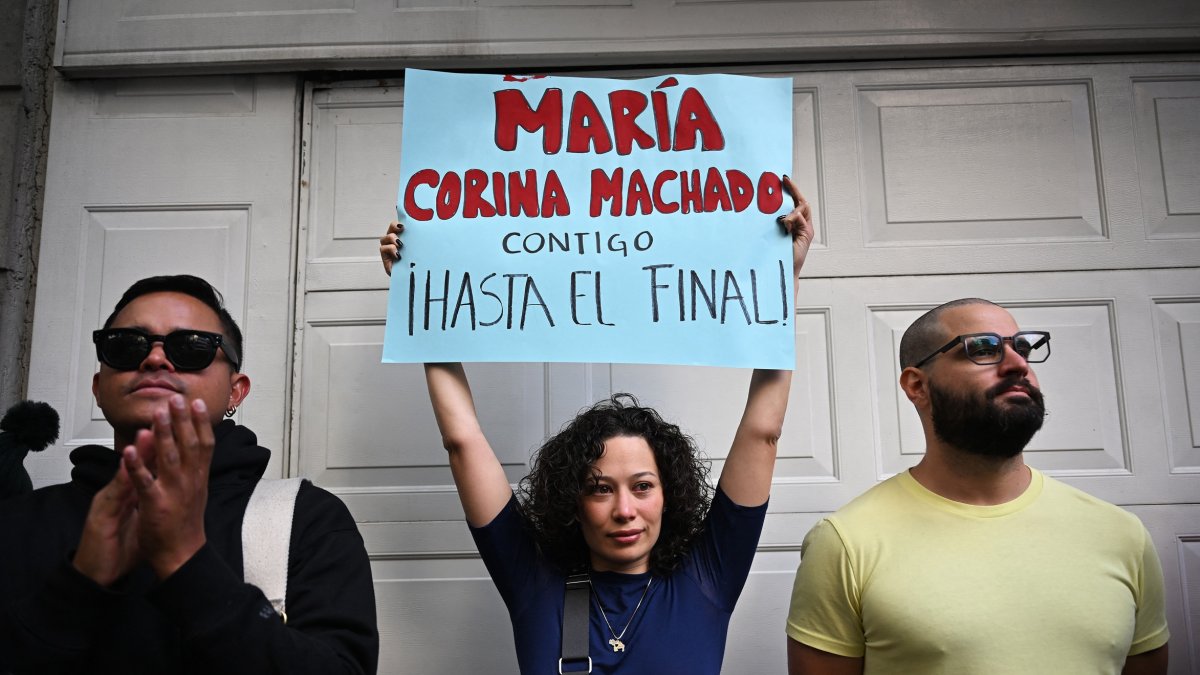 Una mujer sostiene un cartel que dice 'María Corina Machado, contigo hasta el final' durante una protesta en vísperas de la toma de posesión presidencial en la Ciudad de México