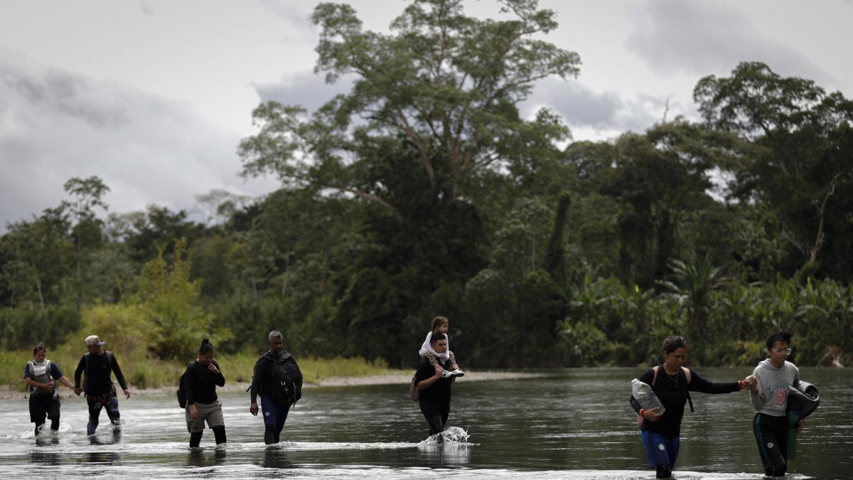 Migrantes que cruzan el río Tuquesa luego de atravesar la selva del Darién, frontera natural entre Colombia y Panamá.