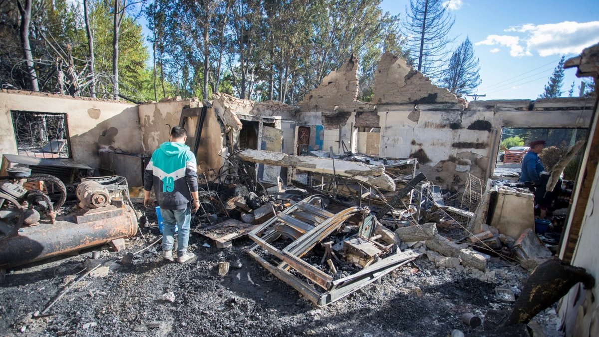 La gente camina entre los escombros de su casa quemada debido a un incendio forestal en Epuyén, en la región patagónica de la provincia de Chubut, el 16 de enero de 2025.