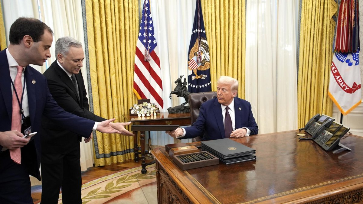 El presidente de Estados Unidos, Donald Trump (derecha), firma órdenes ejecutivas en la Oficina Oval de la Casa Blanca en Washington, DC.