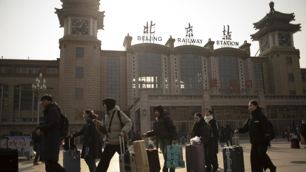 Varios turistas caminan caminoa a la estación de trenes de Pekín.