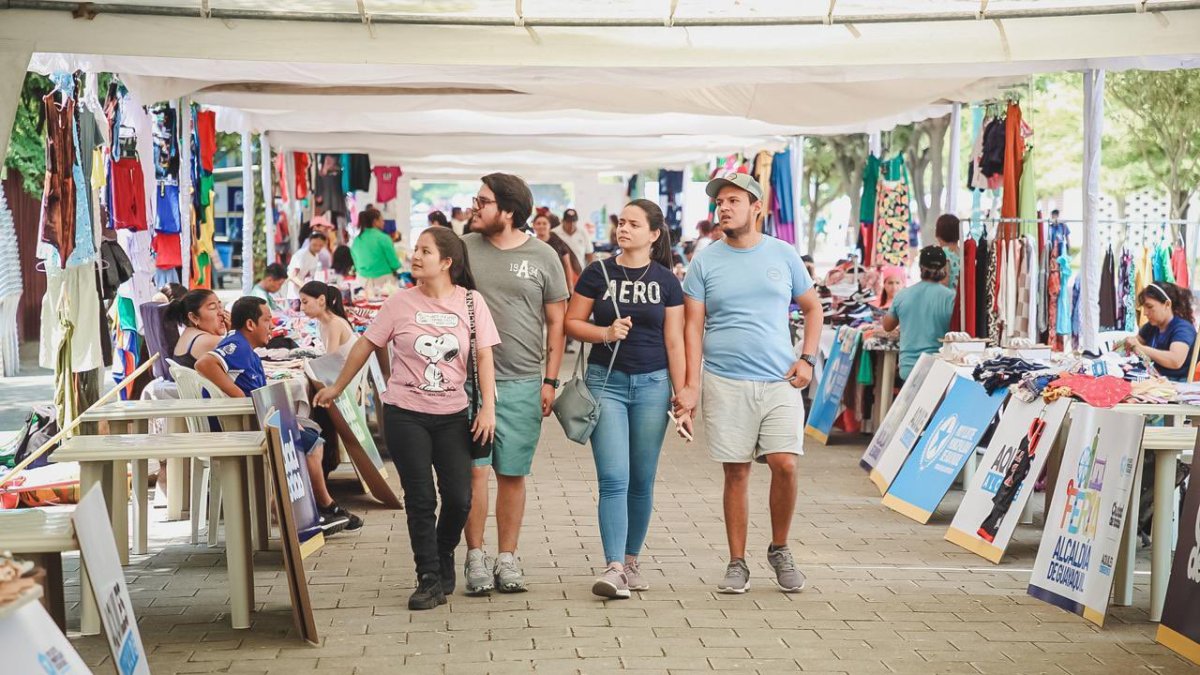 Visitantes recorren la feria de comerciantes en el parque samanes.