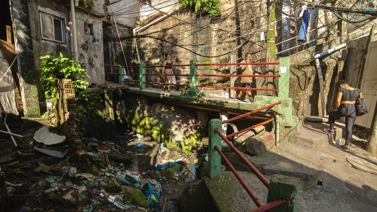 La gente camina en un callejón con aguas residuales a cielo abierto en la favela Rocinha, Río de Janeiro, Brasil, el 18 de noviembre de 2024.