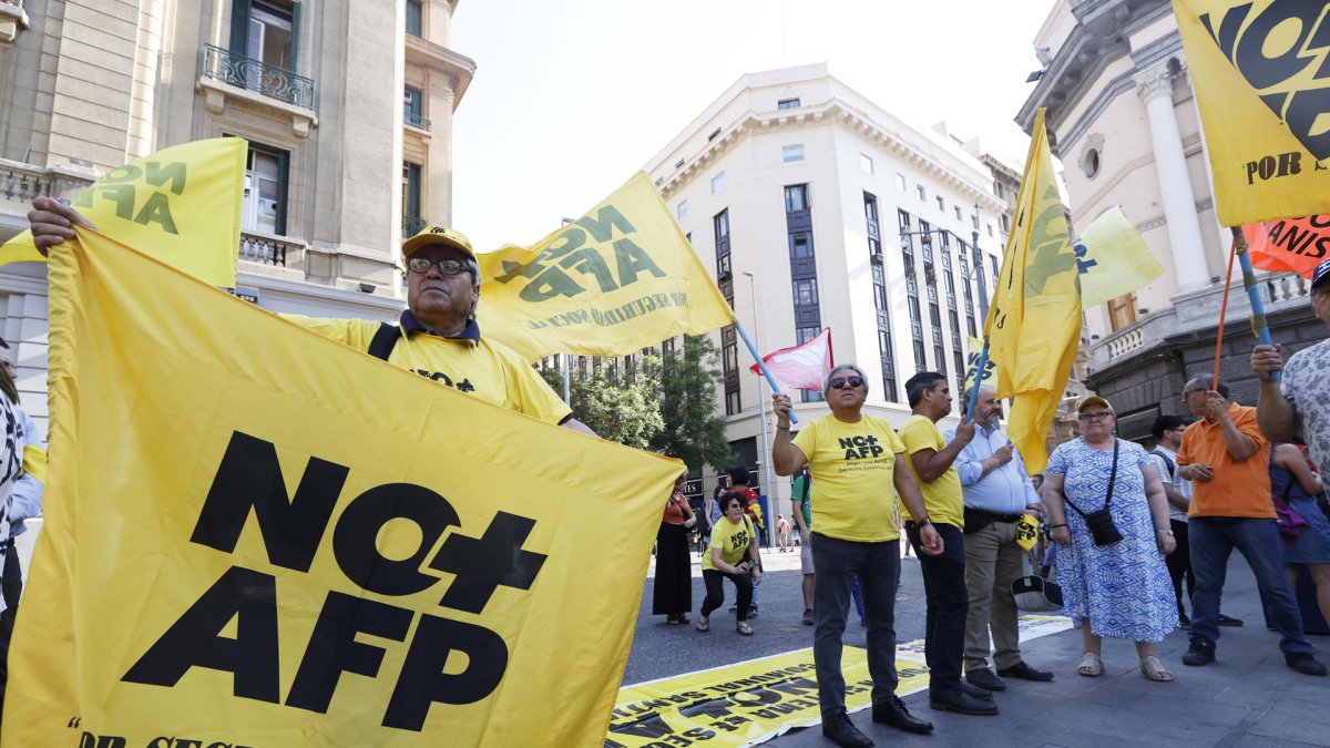 Personas sosteniendo banderas durante una manifestación en contra de las Administradoras de Fondos de Pensiones (AFP), en Santiago (Chile).
