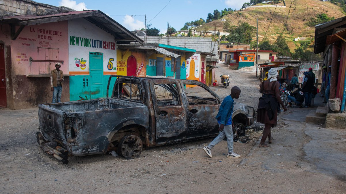 La gente camina junto a un vehículo quemado en Kenscoff, Haití, el 29 de enero de 2025.