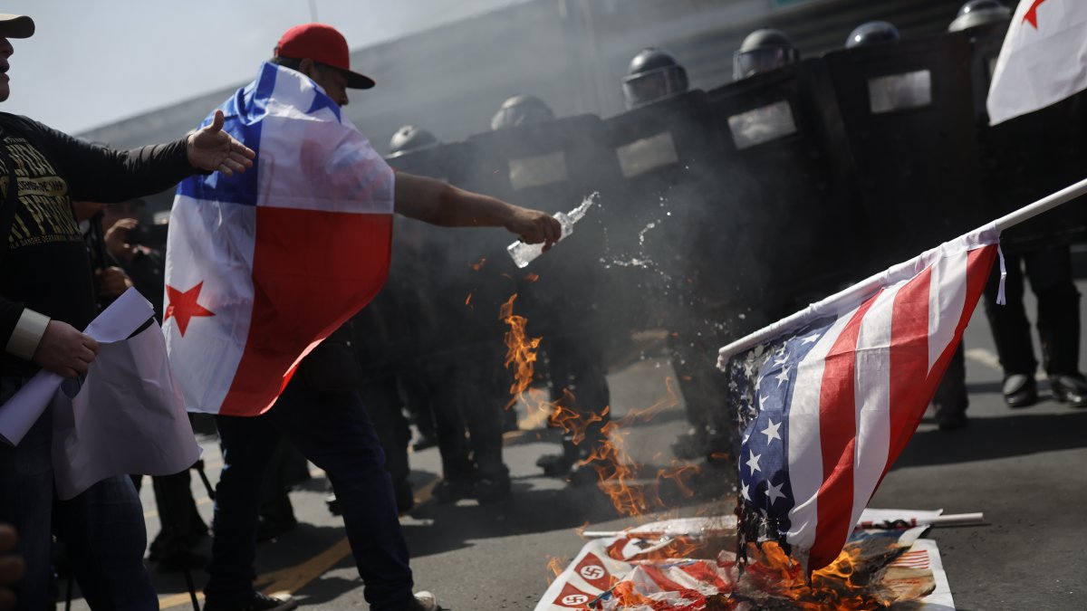 Personas queman una bandera de Estados Unidos durante una protesta por la visita del Secretario de Estado de Estados Unidos, Marco Rubio.