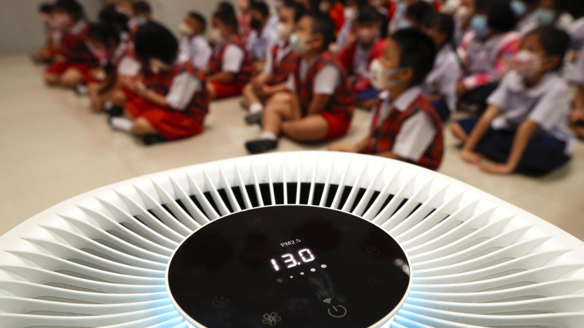 Bangkok. Niños de jardín de infantes se sientan dentro de una habitación equipada con un purificador de aire.