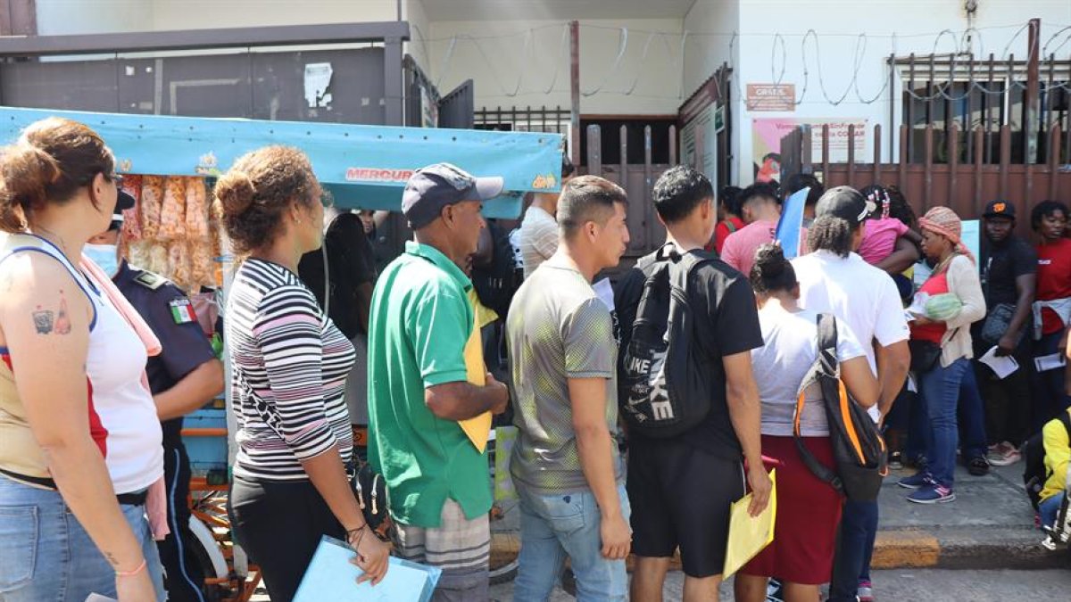 Migrantes hacen fila frente a las instalaciones de la Comisión Mexicana de Ayuda a Refugiados (Comar) este viernes 7 de febrero, en Tapachula (México).