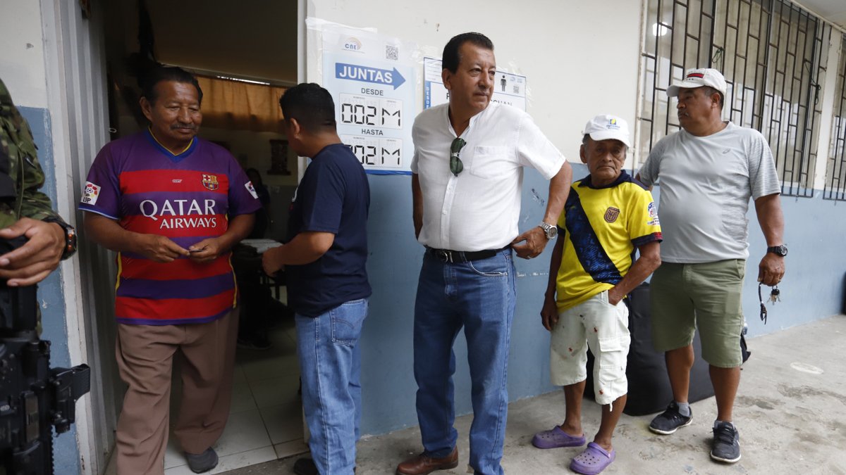 Hombres esperan para votar este domingo, en un puesto de votación en Olón (Ecuador).