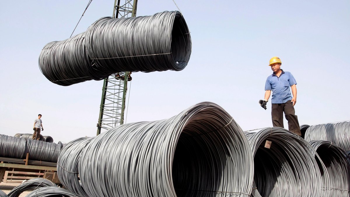 Operarios mientras transportan bobinas de cable de acero para su pesaje en Pekín (China). 