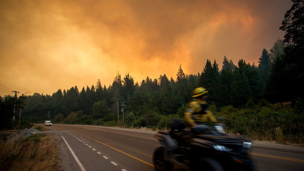 Un bombero conduce una motocicleta hacia un incendio forestal en las montañas de Mallín Ahogado, cerca de El Bolsón, en la provincia patagónica de Río Negro, Argentina, el 9 de febrero de 2025.)