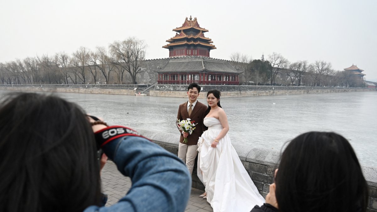Una pareja posa para fotografías de boda en las afueras de la Ciudad Prohibida en Beijing. El año pasado, China experimentó una disminución de una quinta parte en los matrimonios.