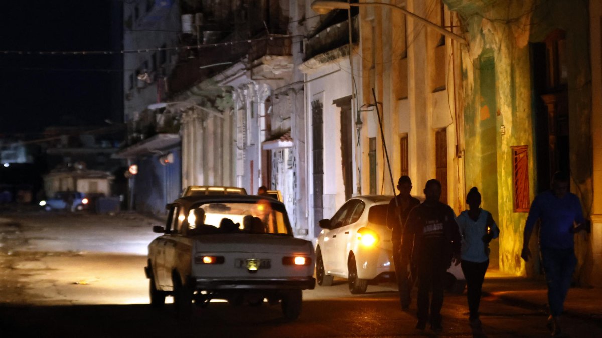 Varias personas caminan por un sector sin servicio eléctrico en La Habana (Cuba).