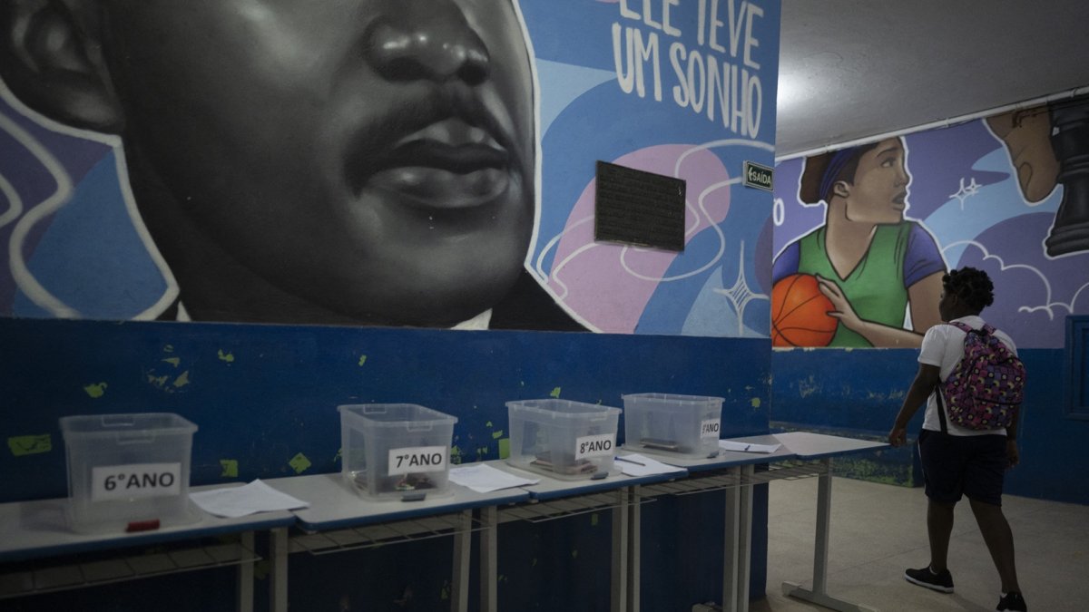 Una estudiante camina hacia su salón de clases después de dejar su teléfono celular en una caja al comienzo del día escolar en la escuela pública Reverend Martin Luther King en Río de Janeiro.