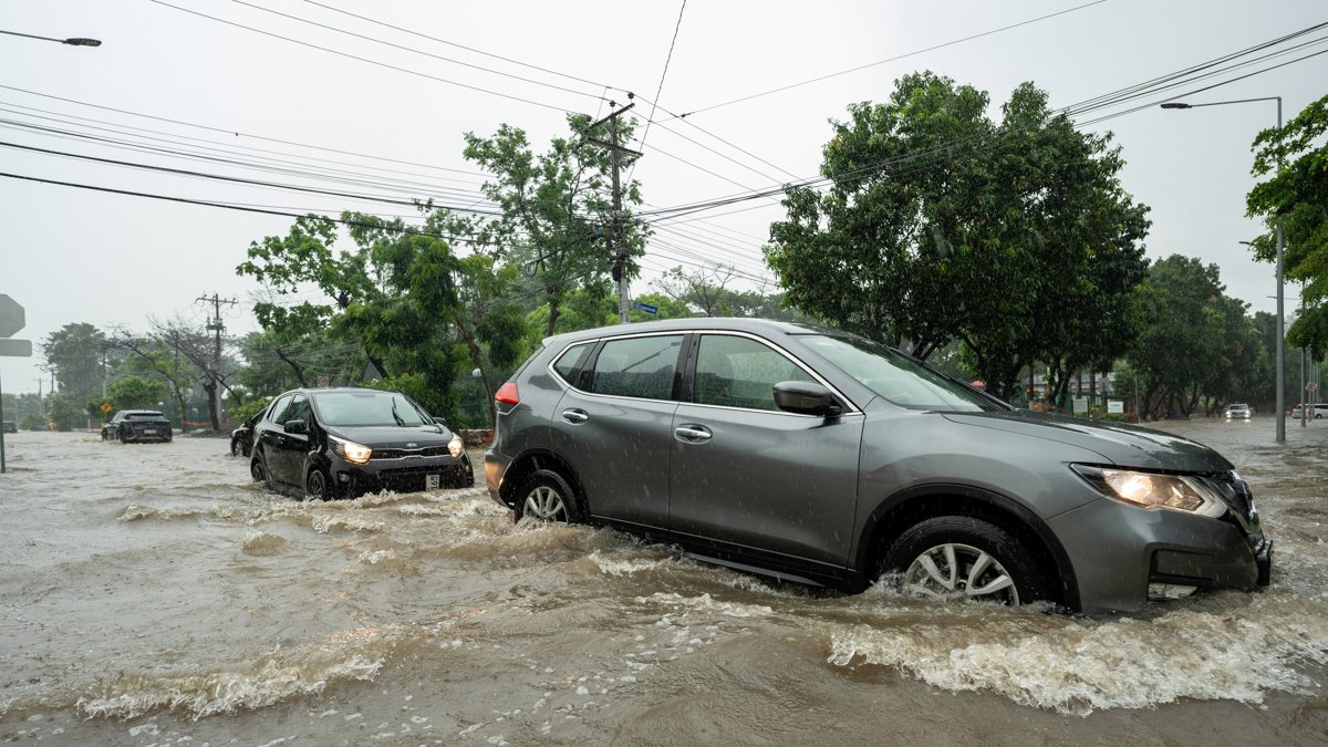 Fotografía de archivo en la que se registró el paso de varios vehículos por una calle inundada en la provincia ecuatoriana de Guayas.
