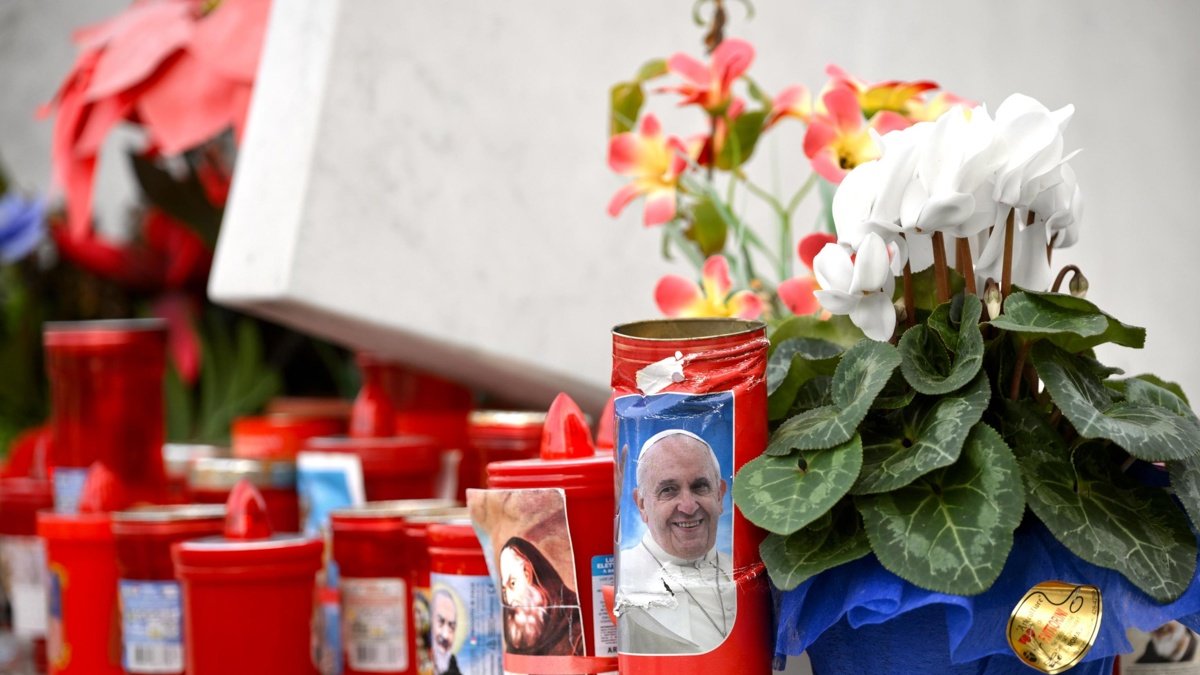 Se colocan flores y velas al pie de una estatua del papa San Juan Pablo II frente al Hospital Universitario Gemelli, en Roma, donde el Papa Francisco está hospitalizado.