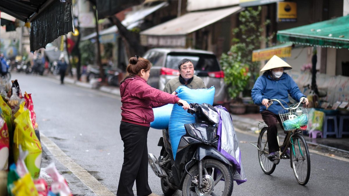 La gente carga bolsas de arroz en una motocicleta en una calle de Hanoi, Vietnam, el 18 de febrero de 2025.