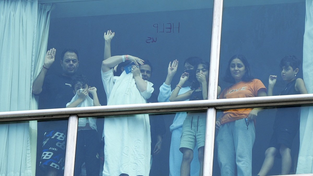 Migrantes deportados desde EE.UU. hacen un gesto mientras miran por la ventana del Hotel Decápolis donde se encuentran hospedados temporalmente en la Ciudad de Panamá, el 18 de febrero de 2025.