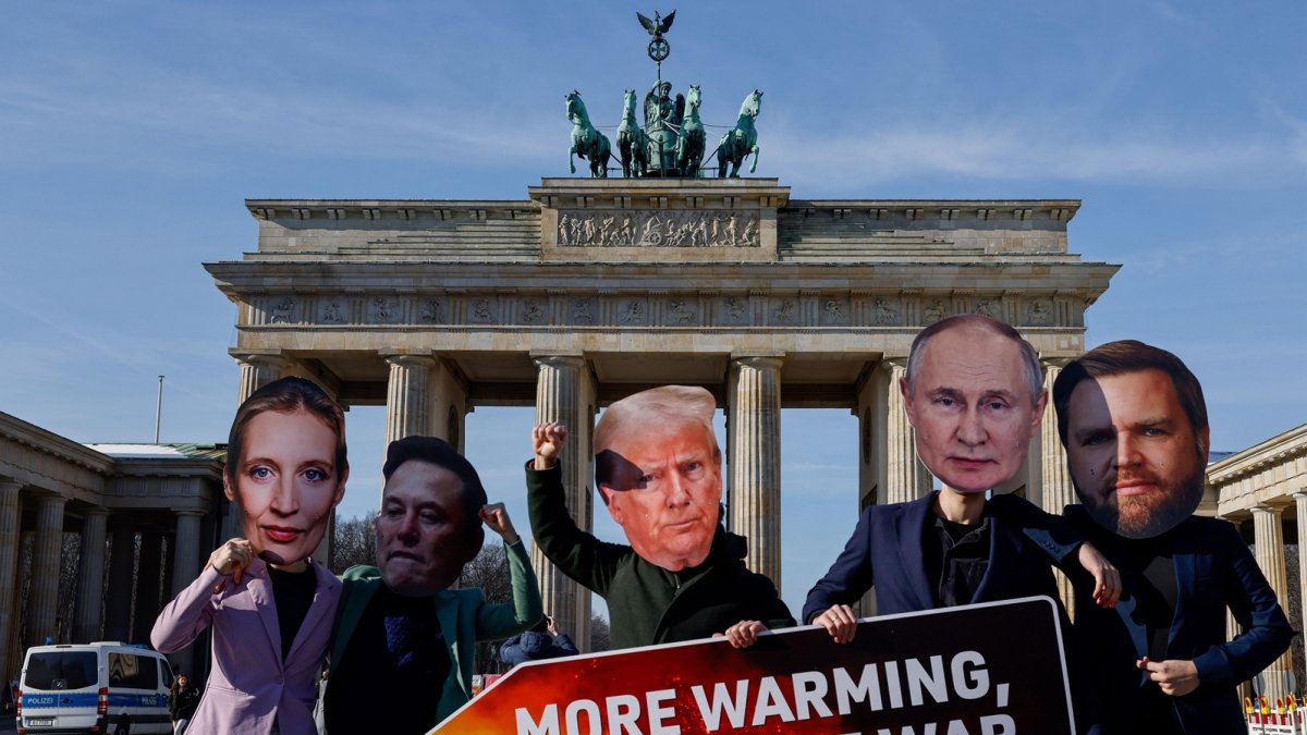 Activistas con máscaras de líderes del mundo sostienen un cartel que dice 