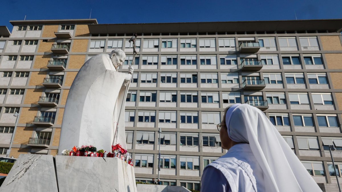 Una monja reza ante una estatua del Papa San Juan Pablo II fuera del Hospital Universitario Gemelli, donde el Papa está hospitalizado por tratamiento de bronquitis.