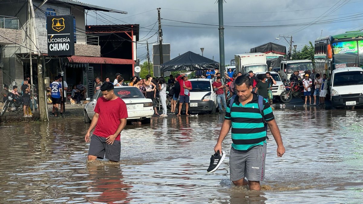 Ciudadanos caminan entre el agua acumulada en una vía en la parroquia Calderón, en Portoviejo, zona rural de Portoviejo.