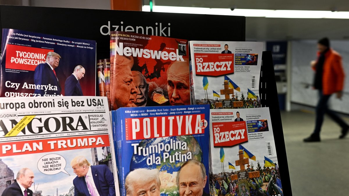 Un hombre camina por un pasaje subterráneo pasando por un quiosco que vende revistas con portadas que representan al presidente Vladimir Putin y al presidente Donald Trump en Varsovia.
