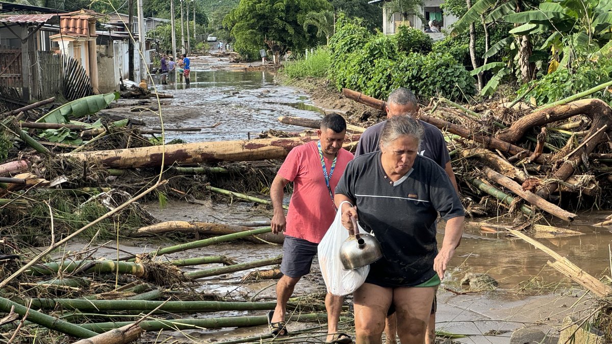 Ana Segovia y otros vecinos caminan entre la palizada de lo que era la vía principal de El Mate, en la parroquia Calderón, Portoviejo en Manabí.