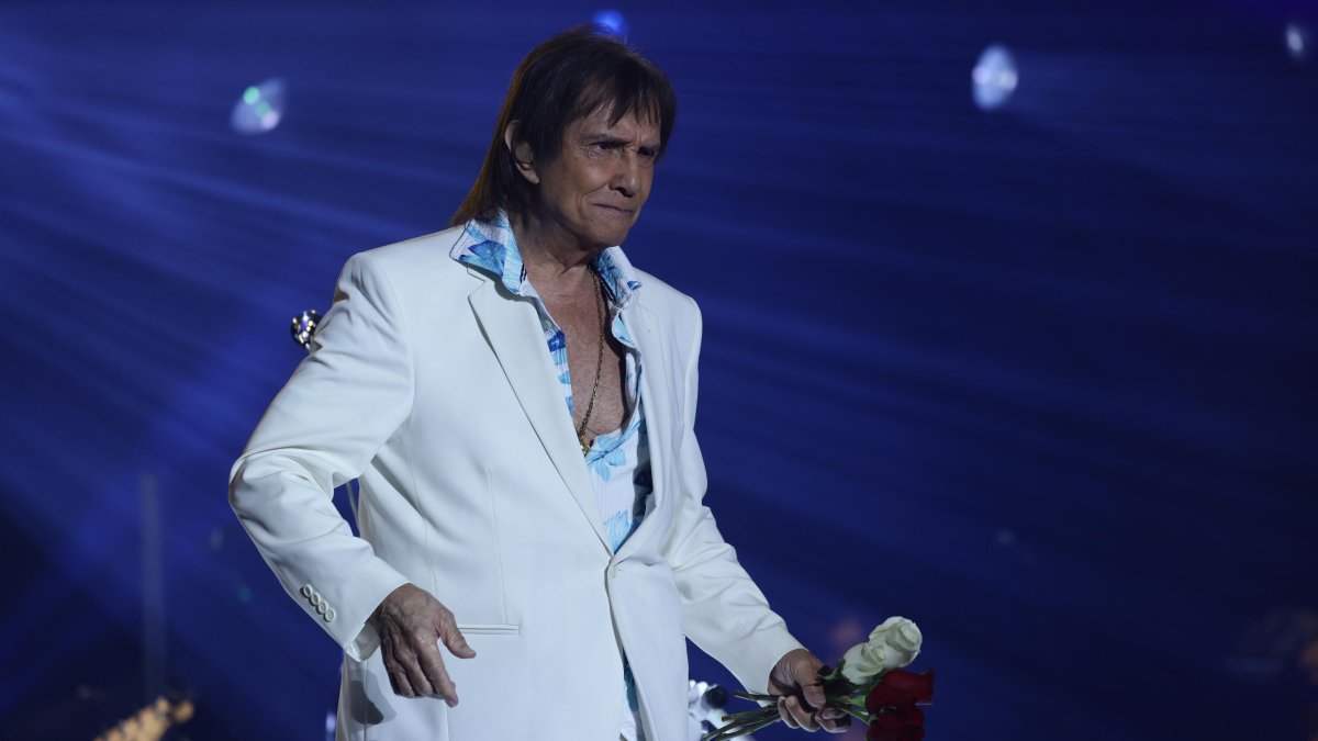 Roberto Carlos en pleno concierto, acompañado de su orquesta, cautivando al público con sus éxitos más icónicos.