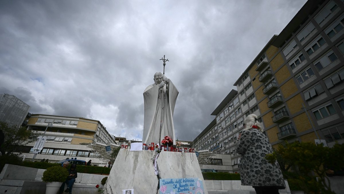 Una mujer reza ante la estatua de Juan Pablo II afuera del hospital Gemelli, donde el Papa Francisco está hospitalizado con neumonía, en Roma, el 28 de febrero de 2025.