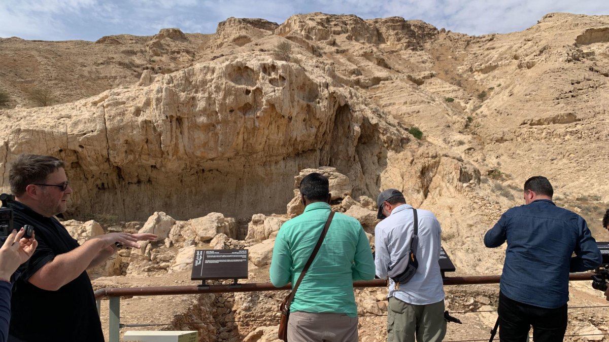 Visitantes que observan un yacimiento al pie de la cordillera de Jebel Faya, en el desierto emiratí de Sharjah.