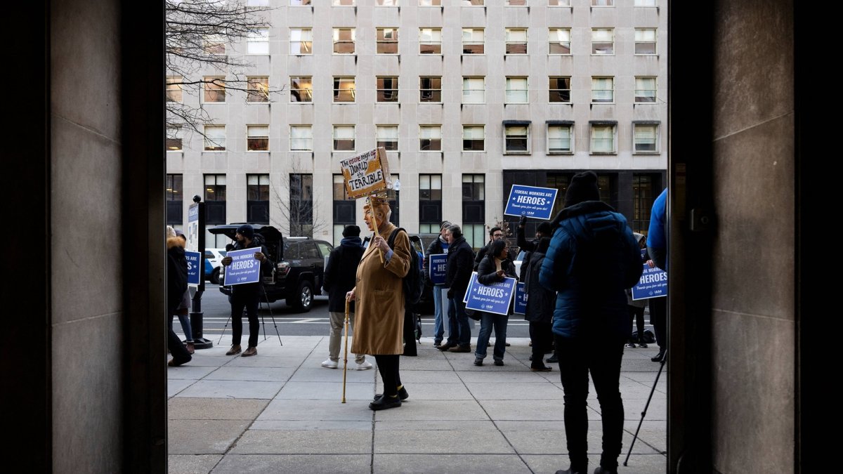 Un manifestante vestido como Donald Trump con una corona sostiene un cartel mientras otros miembros del sindicato IAM, NFFE-IAM, protestas frente a la estación de metro McPherson Square.