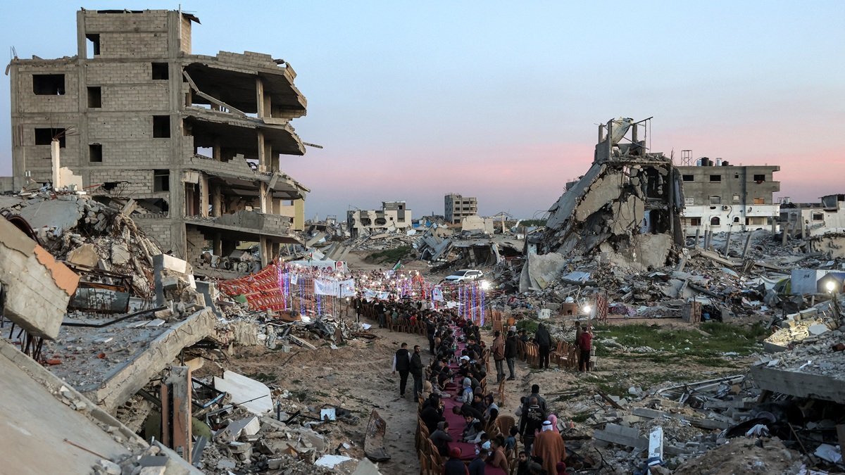 La gente se reúne entre los escombros de los edificios destruidos para celebrar una reunión masiva para romper el ayuno del iftar en el segundo día del mes sagrado musulmán del Ramadán.